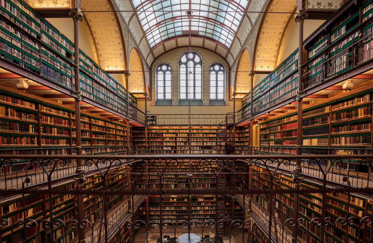 hero-img-01 Explore the ornate and historic library interior at Amsterdam's Rijksmuseum, filled with ancient books and architectural beauty.